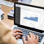 Duas pessoas analisando gráficos de marketing digital em um laptop durante uma reunião